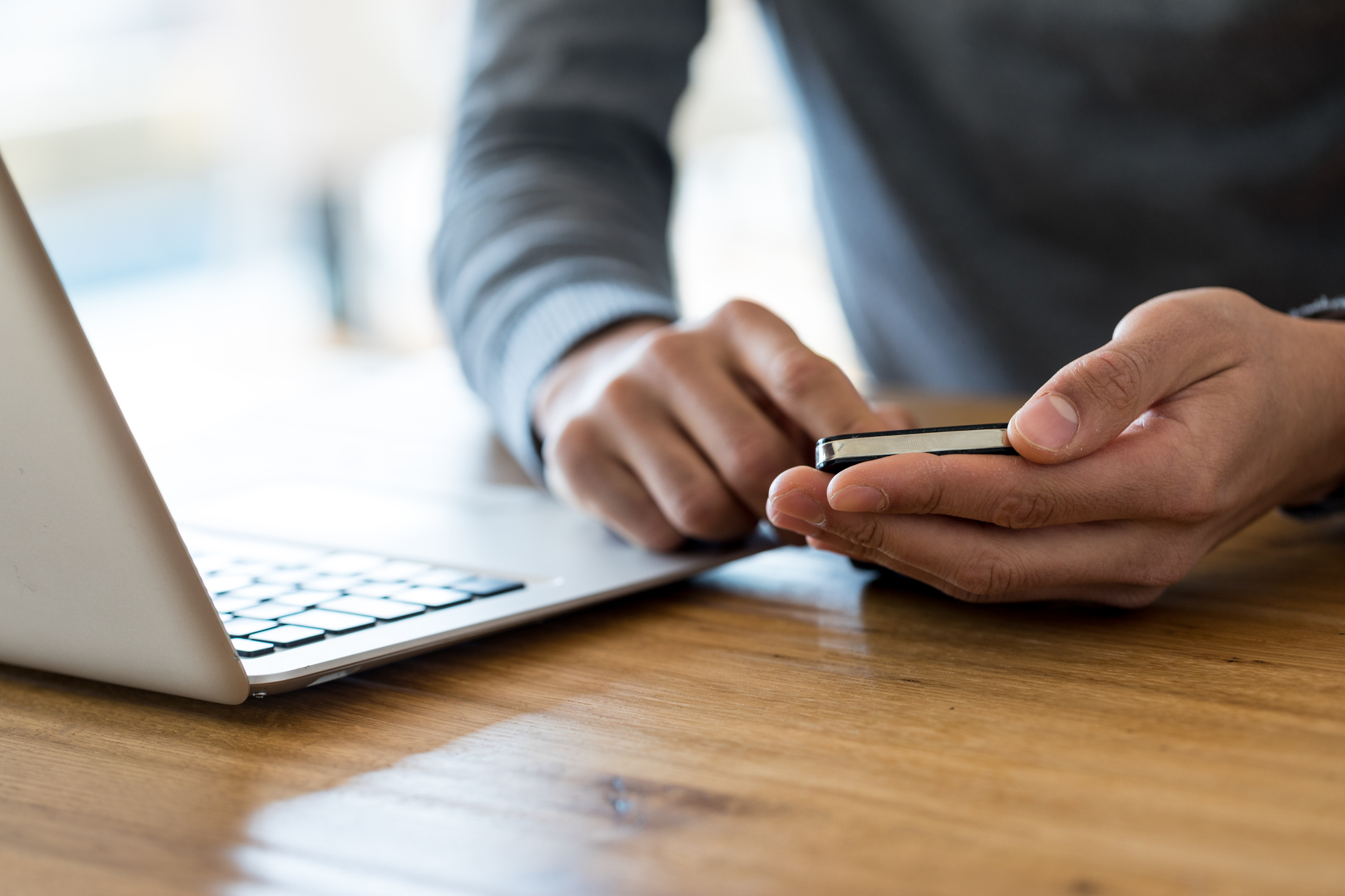 man's hands typing on cell phone